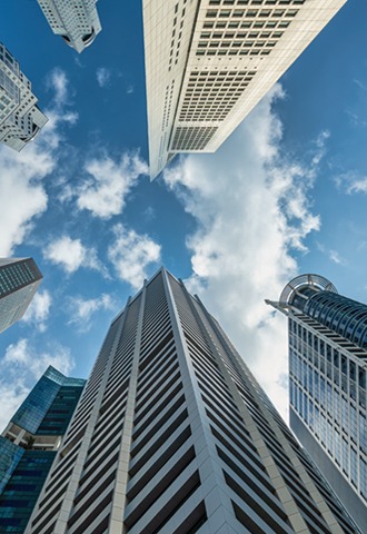 Upward view of modern skyscrapers and office buildings against a blue sky with white clouds