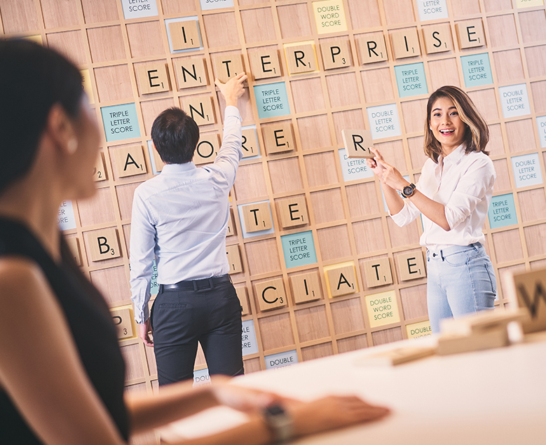 Lady holding an alphabet while playing Scrabble