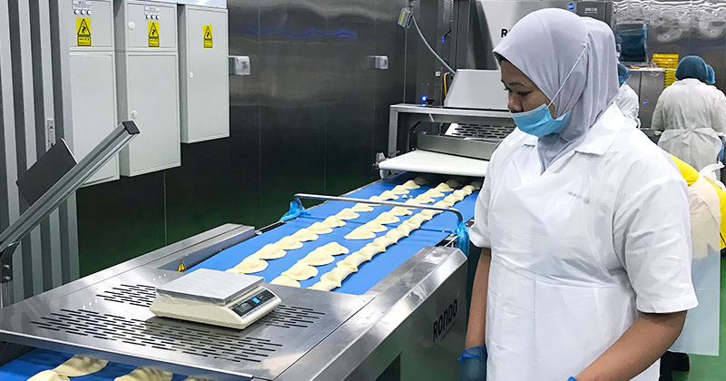 Behind the scenes at Old Chang Kee’s production line: Employees sorting the curry puffs after the dough has been automatically cut and filled